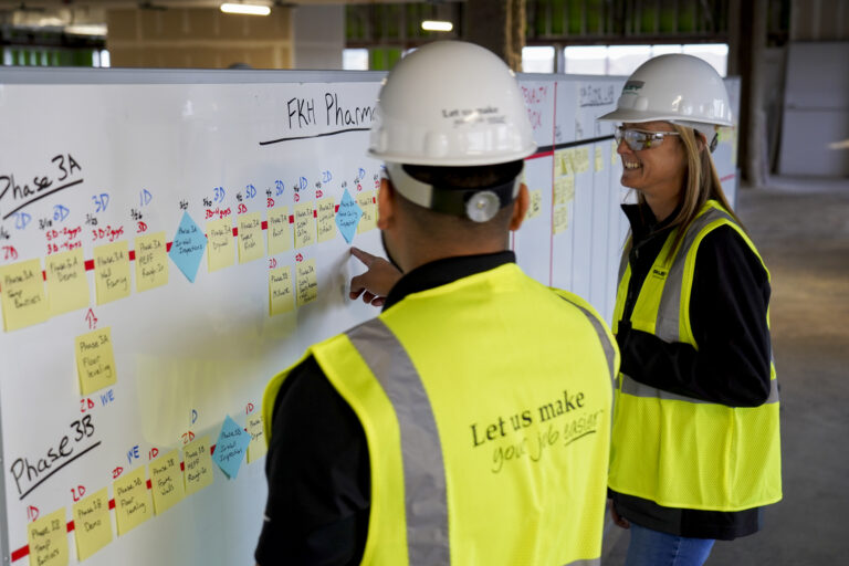 man and woman collaborating over pull plan in construction job trailer
